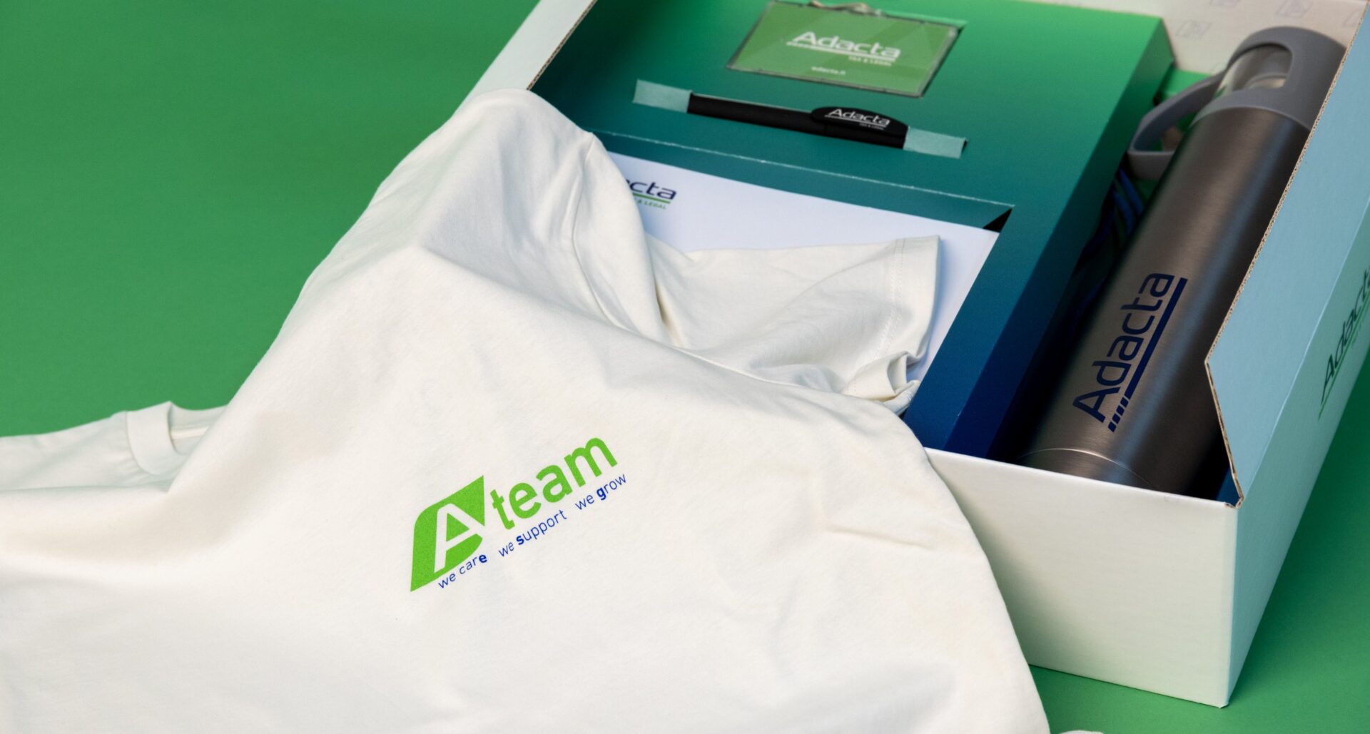 Kit di benvenuto con t-shirt personalizzata Adacta in una scatola brandizzata.